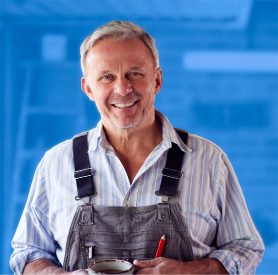 Smiling handyman in overalls holding tools.